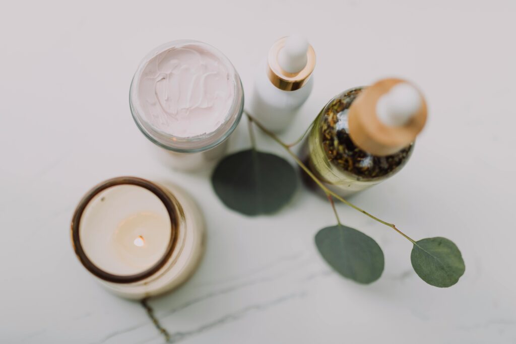 Calming spa scene featuring skincare items, a candle, and eucalyptus leaves for relaxation.